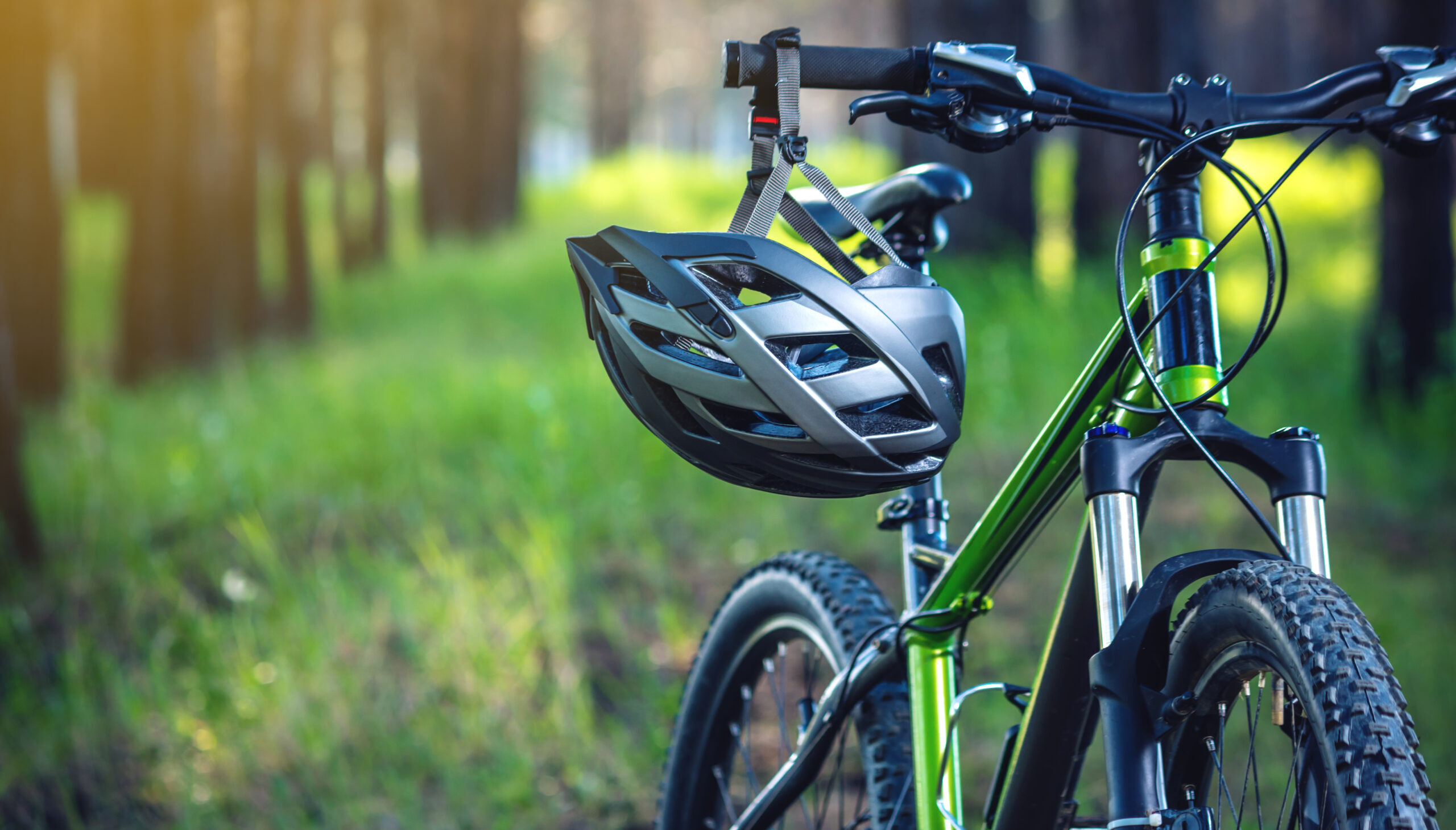 Sports helmet on a green mountain bike in the Park among the trees. Concept protection during active and healthy lifestyle
